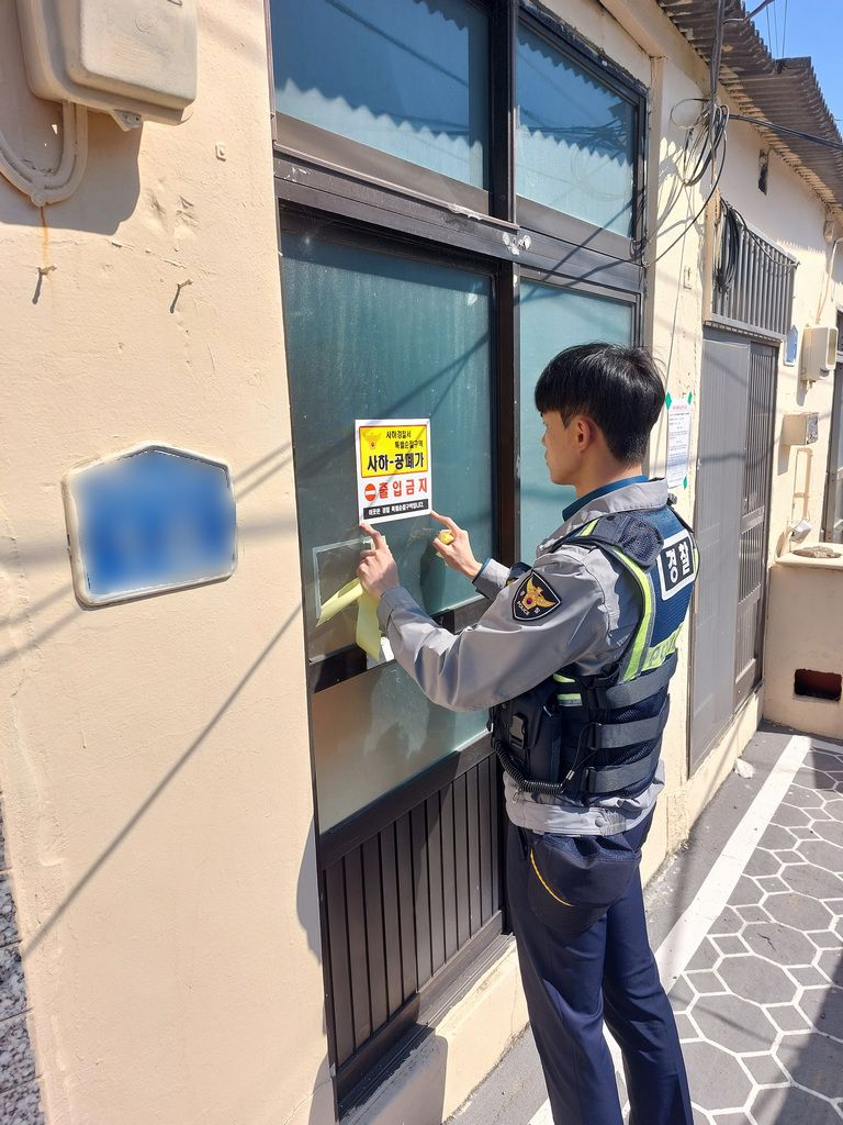부산 경찰이 빈집에 방문해 출입급지 경고문을 부착하고 있다. 부산경찰청 제공