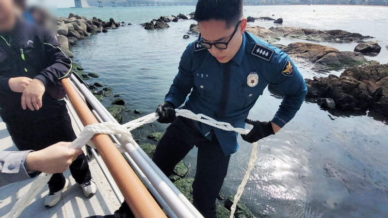 지난달 29일 오후 2시 해안산책로를 걷던 외국인 여성이 바닷가에 가방을 빠뜨려 경찰이 직접 로프를 타고 바닷가로 내려가 가방을 수거했다. 부산경찰청 제공