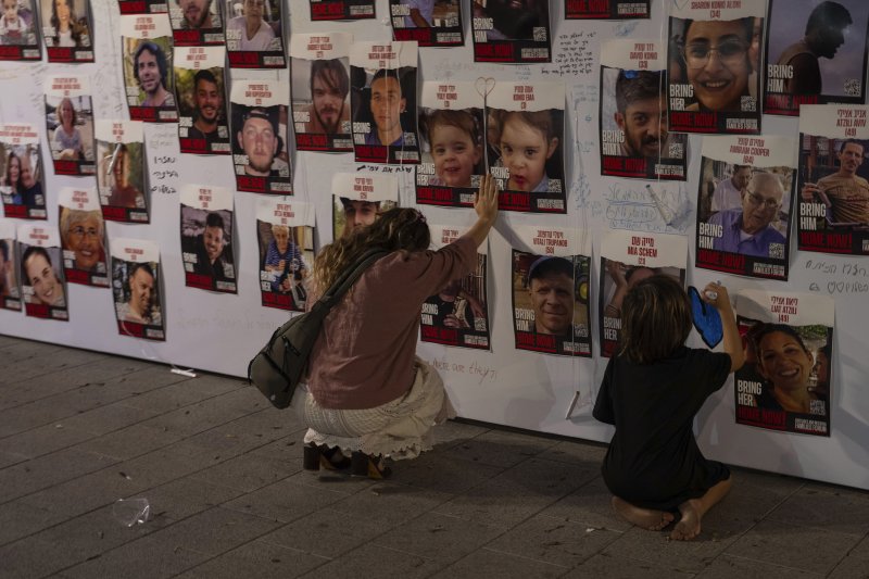 지난해 10월 21일 이스라엘 텔아비브에서 한 시민이 가자지구에 끌려간 인질들의 사진에 손을 얹고 있다.AP뉴시스