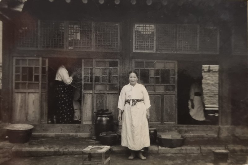 [서울=뉴시스]1950년대 최종건 SK 창업회장과 최종현 선대회장의 모친인 이동대 여사가 한옥 부엌 앞에서 식사를 준비하고 있다. (사진 = SK) 2024.04.08. photo@newsis.com *재판매 및 DB 금지
