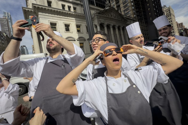 8일(현지시각) 미국 뉴욕 맨해튼의 한 식당 직원들이 쉬는 시간을 이용해 달이 태양을 완전히 가리는 개기일식을 관측하고 있다.AP뉴시스