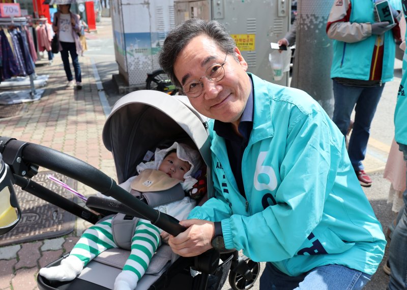 제22대 총선에 출마한 새로운미래 이낙연 대표가 9일 광주 광산구 거리에서 한 아이 곁에서 미소 짓고 있다.
