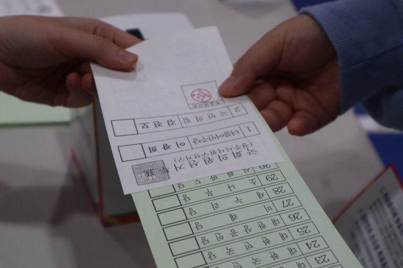 제22대 국회의원 선거날인 10일 유권자들이 투표용지를 건네받고 있다. 뉴스1