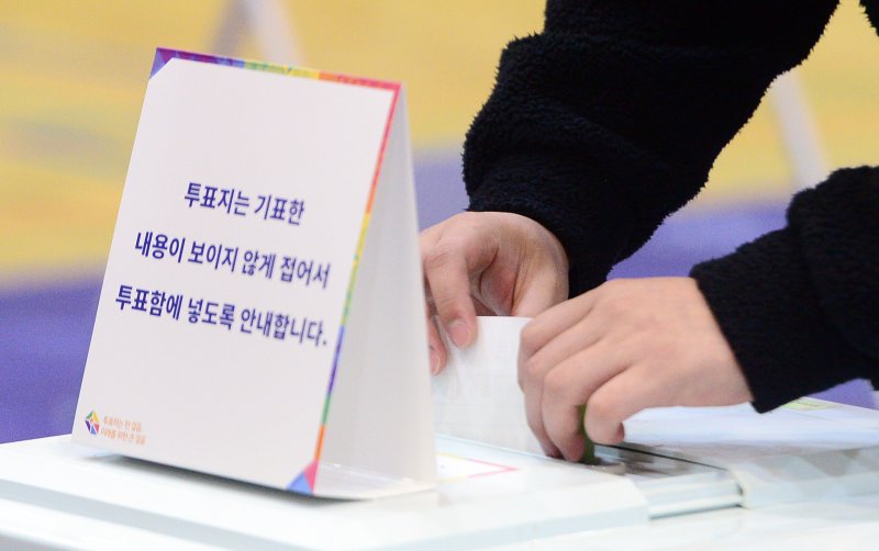 제22대 국회의원 선거 본투표날인 10일 광주 서구 상무고등학교에 마련된 투표소에서 유권자들이 투표용지를 투표함에 넣고 있다. 뉴스1