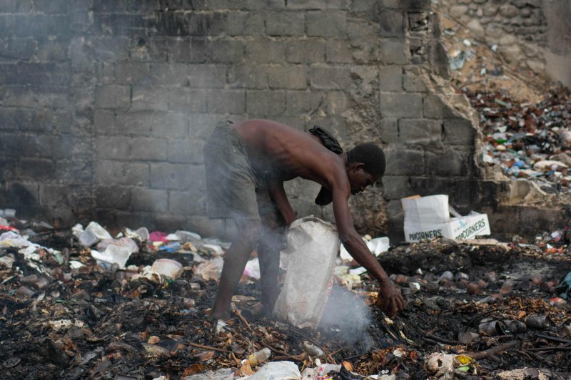 지난 13일(현지시간) 아이티 수도 포르토프랭스에서 한 남성이 타고 있는 쓰레기를 뒤지고 있다. AFP연합뉴스)