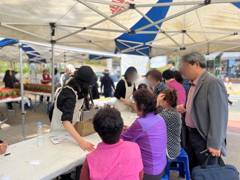 화분 나눔 행사에 참여한 안산 주민들이 세월호와 관련해 이야기꽃을 피우며 추모 메시지를 작성하고 있다. / 뉴스1 박혜연 기자