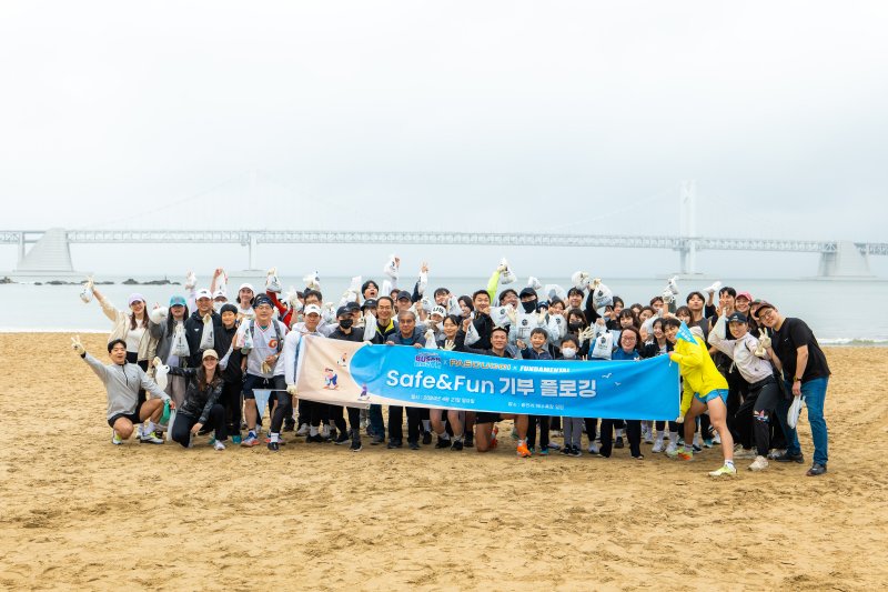 부산관광공사와 시민들이 '지구의 날'을 기념해 지난 21일 광안리해수욕장에서 기부 플로깅 캠페인을 연 가운데 참여자들이 기념촬영을 하고 있다. 부산관광공사 제공