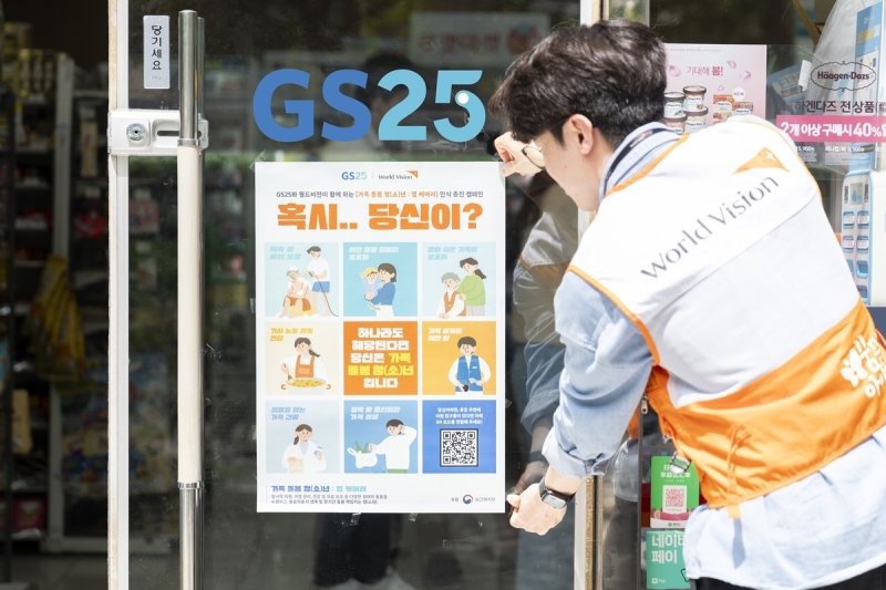 월드비전 직원이 지난 23일 서울 영등포구 GS25 매장에 '가족돌봄청소년 캠페인' 포스터를 부착하고 있다. 월드비전 제공