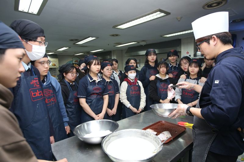 BBQ 치킨대학 캠프에 참여한 고등학생들이 치킨을 만드는 방법에 대한 설명을 듣고 있다.