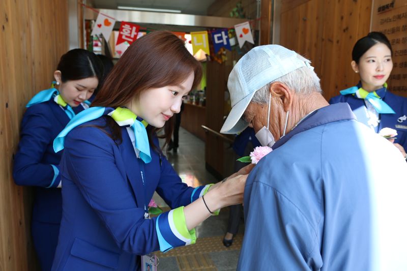 에어부산 캐빈 승무원이 강서노인종합복지관에서 어르신들에게 카네이션을 달아드리고 있다. 에어부산 제공