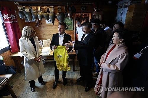 에마뉘엘 마크롱 프랑스 대통령이 프랑스 남서부 오트피레네의 콜 뒤 투르말레로에서 시진핑 중국 국가 주석에게 7일(현지시간) 투르드프랑스 2회 연속 우승자인 요나스 빙에고르의 사인이 담긴 노란색 유니폼을 선물하고 있다. AP 연합뉴스