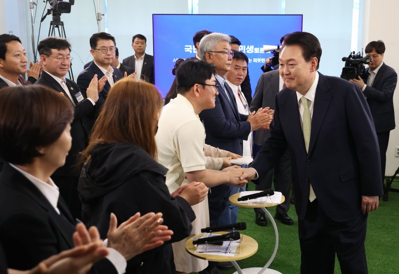 윤석열 대통령이 14일 서울 중구 서울고용복지플러스센터에서 열린 스물다섯번째 '국민과 함께하는 민생토론회'에 입장하며 참석자들과 악수하고 있다. 이날 토론회는 '고맙습니다, 함께 보듬는 노동현장'을 주제로 진행됐다. [대통령실통신사진기자단] 연합뉴스