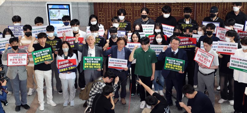 부산대학교 의과대학 정원 증원 학칙 개정안을 재심의하는 교무회의 열린 21일 오후 부산 금정구 부산대 대학본부 로비에서 의대 교수진과 학생들이 학칙 개정안 부결을 촉구하는 성명서를 발표한 뒤 구호를 외치고 있다. 뉴시스 제공