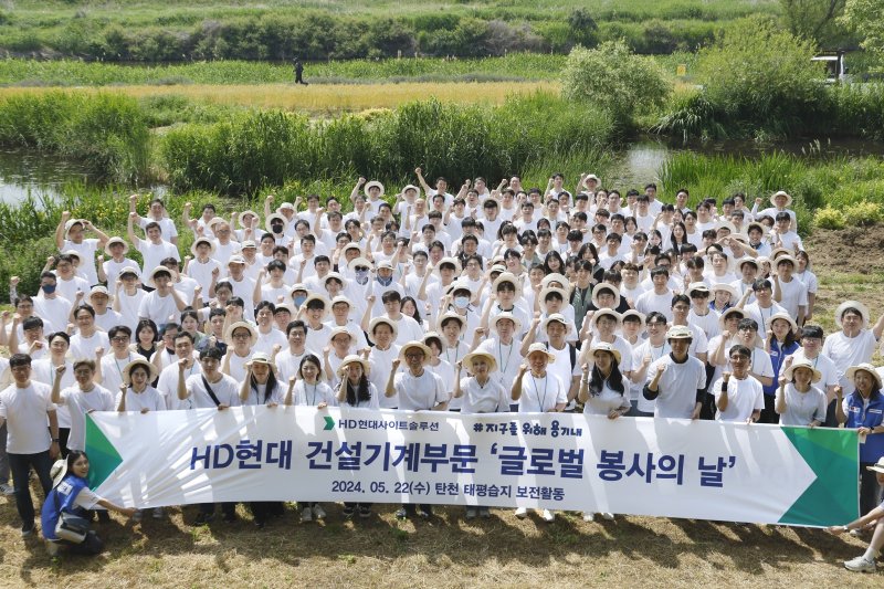 HD현대 건설기계 3사 임직원들이 22일 '글로벌 봉사의 날'을 맞아 경기 성남시 탄천 태평습지생태원에서 기념촬영을 촬영하고 있다. HD현대사이트솔루션 제공