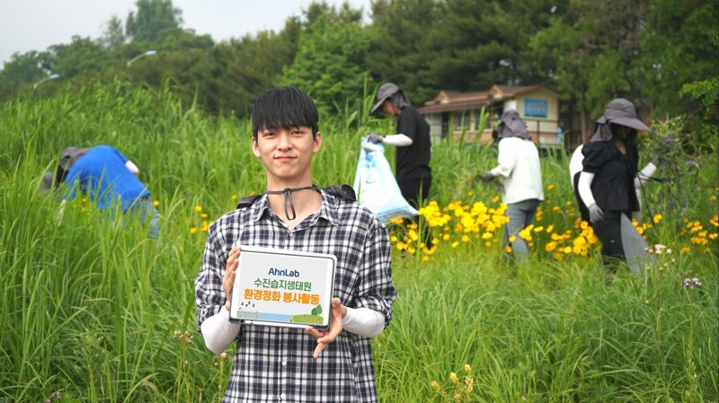 안랩 관계자가 지난 24일 경기도 성남시 탄천 수진습지생태원서 환경정화 봉사활동을 하면서 기념사진을 찍고 있다. 안랩 제공