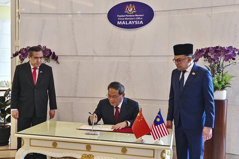리창 중국 총리(가운데)가 지난 6월 19일(현지시간) 말레이시아 푸트라자야의 총리실에서 안와르 이브라힘(오른쪽) 말레이시아 총리가 지켜보는 가운데 방명록에 서명하고 있다. AP 뉴시스