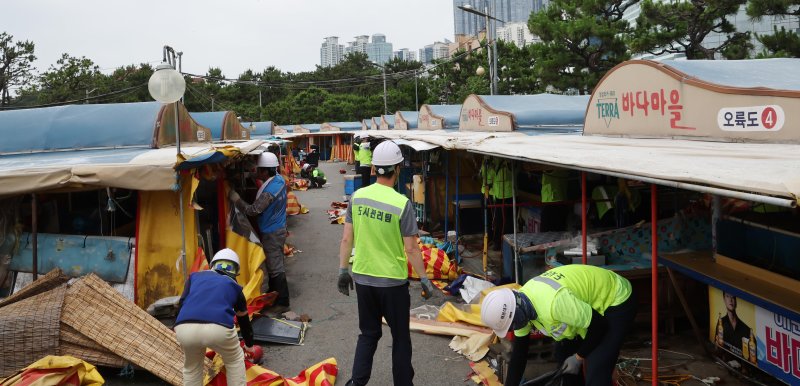 [부산=뉴시스] 하경민 기자 = 1960년대 초부터 영업을 한 부산 해운대 바다마을 포장마차촌이 추억 속으로 사라졌다. 25일 해운대구청 관계자들이 중장비를 동원해 포장마차촌을 철거하고 있다. 이 포장마차촌은 시유지 무단점용과 무신고 영업행위 등 논란이 끊이지 않았고, 해운대구는 2021년 상인들과 2년6개월의 유예기간을 거쳐 올 1월31일 자진 철거하기로 합의하고 이날 최종 철거에 나섰다. 2024.06.25. yulnetphoto@newsis.com