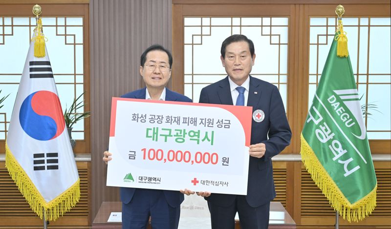 홍준표 대구시장(왼쪽)이 26일 대구시청 산격청사 접견실에서 박명수 대한적십자사 대구지사 회장에게 화성 공장 화재 피해 지원 성금 1억원을 전달하고 함께 포즈를 취했다. 대구시 제공