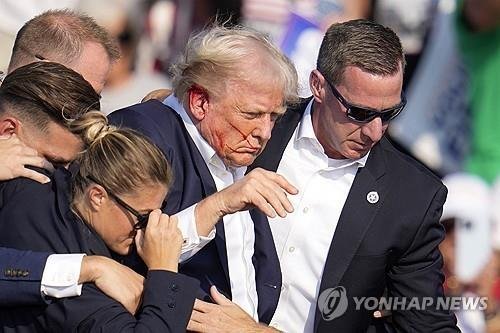 트럼프 전 대통령이 경호원들의 부축을 받으며 유세장을 빠져나가고 있다. /AP=연합뉴스