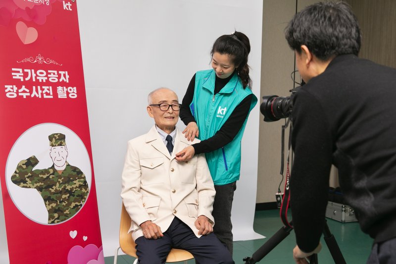 16일 서울 도봉구 서울북부보훈지청에서 열린 KT의 '국가유공자 대상 사랑의 봉사활동'에서 국가 유공자 어르신이 장수사진을 찍고 있다. 사진=KT 제공