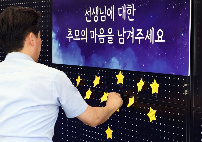 서이초 교사 순직 1주기(18일)를 앞둔 15일 서울 종로구 서울시교육청에 마련된 서이초 교사 1주기 추모 공간에서 교육청 직원이 추모의 마음을 담아 쓴 글을 붙이고 있다. 2024.7.15/뉴스1 ⓒ News1 박정호 기자