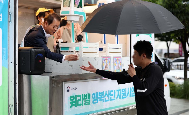 이정식 고용노동부 장관이 23일 서울 구로구 한국산업단지공단 서울지역본부 앞에서 인근 직장인들에게 아이스크림을 나눠주며 일·가정 양립제도 등 워라밸 행복산단 지원사업을 홍보하고 있다. <뉴시스>