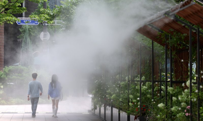 서울 전역에 올여름 첫 폭염경보가 발령된 가운데 서울시는 폭염대응체계를 2단계로 격상했다. 장마가 소강상태에 접어 들면서 무더운 날씨를 보인 24일 오후 서울시청 앞에서 행인들이 더위를 피해 쿨링포그 아래로 지나가고 있다. 뉴시스