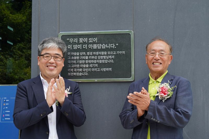 25일 강원도 평창군에서 열린 국립한국자생식물원 연구센터 준공식 및 개원식에서 임상섭 산림청장(왼쪽)과 김창렬 기증자가 기증 동판 앞에서 박수치고 있다. 산림청 제공