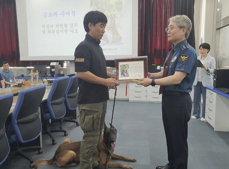 9일 오전 부산경찰청에서 수색견 담당 박현철 경위와 체취증거견 야크의 공로패 수여식이 열렸다. 사진은 우철문 부산경찰청장(오른쪽)이 박현철 경위(왼쪽)와 수색견 야크에게 공로패를 수여하는 모습. 사진 = 최승한 기자