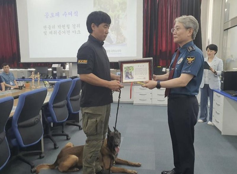 지난 9일 부산경찰청에서 우철문 부산경찰청장(오른쪽)이 박현철 경위와 수색견 야크에게 공로패를 수여하고 있다. 사진 = 최승한 기자