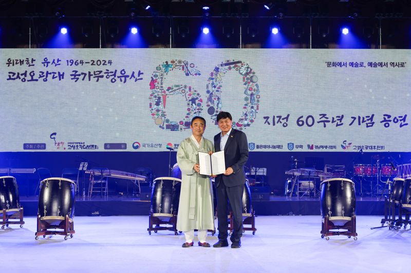 지난 15일 경남 고성군 국민체육센터에서 열린 '고성오광대 국가무형유산 지정 60주년 기념 공연' 개막식에서 최재호 무학 회장(오른쪽)이 전광열 고성오광대보존회 대표에게 후원금을 전달한 후 기념사진을 촬영하고 있다. 무학 제공