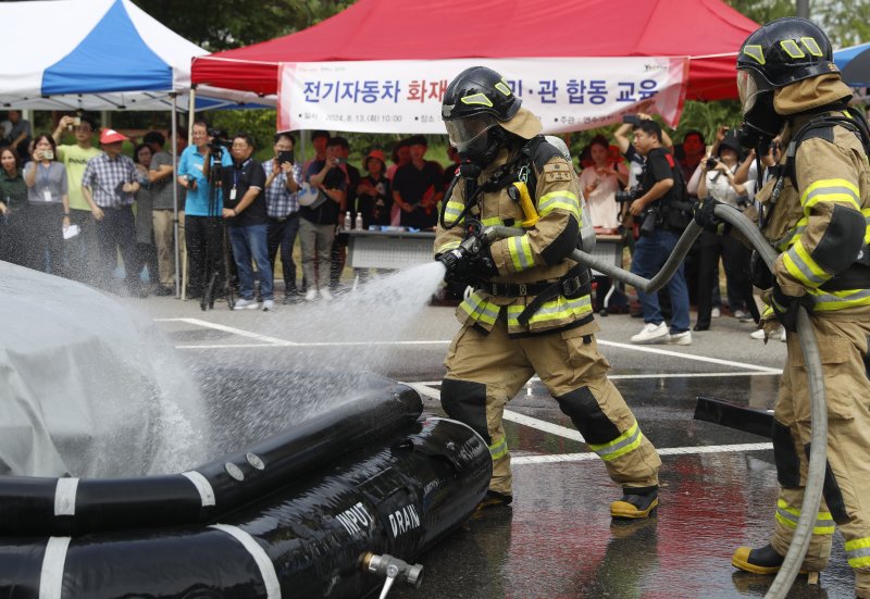 [인천=뉴시스] 김동영 기자 = 지난 13일 오전 인천 연수구 송도2동 행정복지센터 옆 주차장에서 열린 ‘전기자동차 화재 대응 민·관 합동 교육’에서 소방대원들이 전기차 수조를 전개하고 있다. 이날 교육은 연수구청과 송도소방서 주최로 열렸으며, 지역 주민과 공무원 등 200여 명이 참여했다. 2024.08.13. dy0121@newsis.com