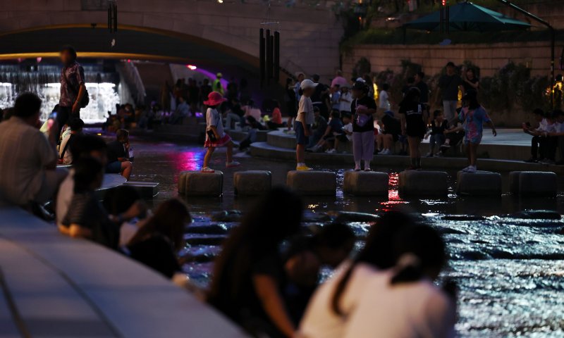 [서울=뉴시스] 전신 기자 = 지난 19일 서울 중구 청계천에서 시민들과 외국인 관광객들이 물에 발을 담그는 등 더위를 식히고 있다. 지난 16일 서울에 26일째 열대야가 나타나 역대 최장 열대야 기록을 경신한 가운데 이날까지 29일째 열대야가 이어지고 있다. 2024.08.19. photo1006@newsis.com