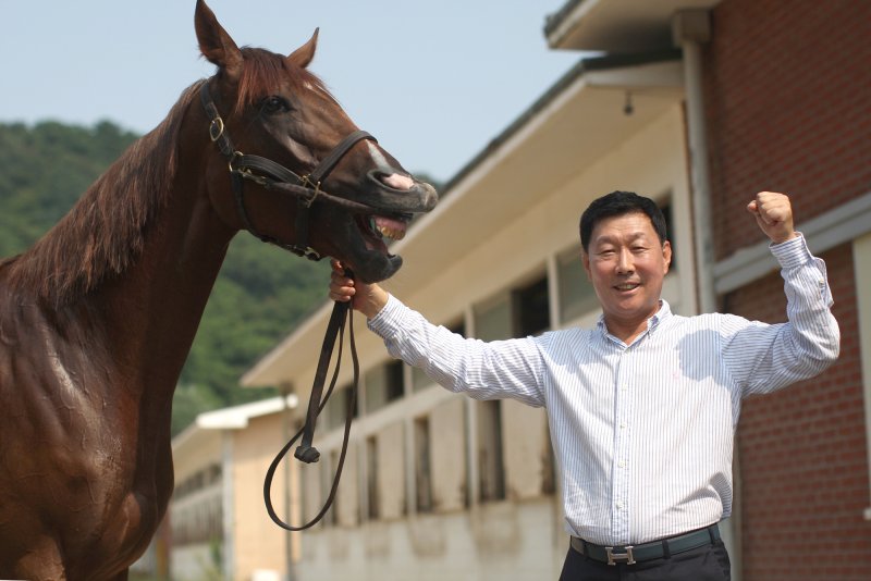 한국마사회 렛츠런파크 부산경남의 김영관 조교사가 지난 23일 '원더드래곤'의 우승으로 한국 경마 조교사 역대 최다 1500승 신기록을 세운 뒤 포즈를 취하고 있다. 한국마사회 제공