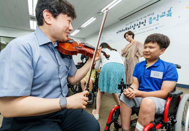 상상인그룹 ‘아카데미 상상인’에 참여한 휠체어 사용 아동이 개별 코칭을 받고 있다. / 사진=상상인그룹 제공