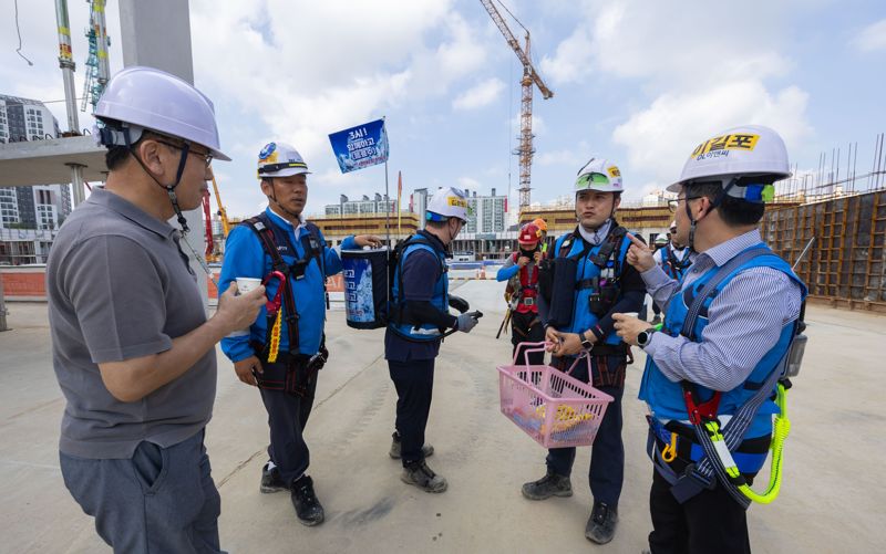 지난 2일 인천 서구 검단 아파트 현장을 찾은 이길포 최고안전책임자(오른쪽 첫 번째)와 현장관계자 등이 근로자에게 물과 빙과류를 제공하고 있다. DL이앤씨 제공