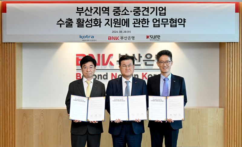 KOTRA 강병수 부산지원단장과 BNK부산은행 손대진 고객기획본부장, 한국무역보험공사 은종철 부산지역본부장(왼쪽부터)이 업무협약서를 들고 포즈를 취하고 있다. 부산은행 제공