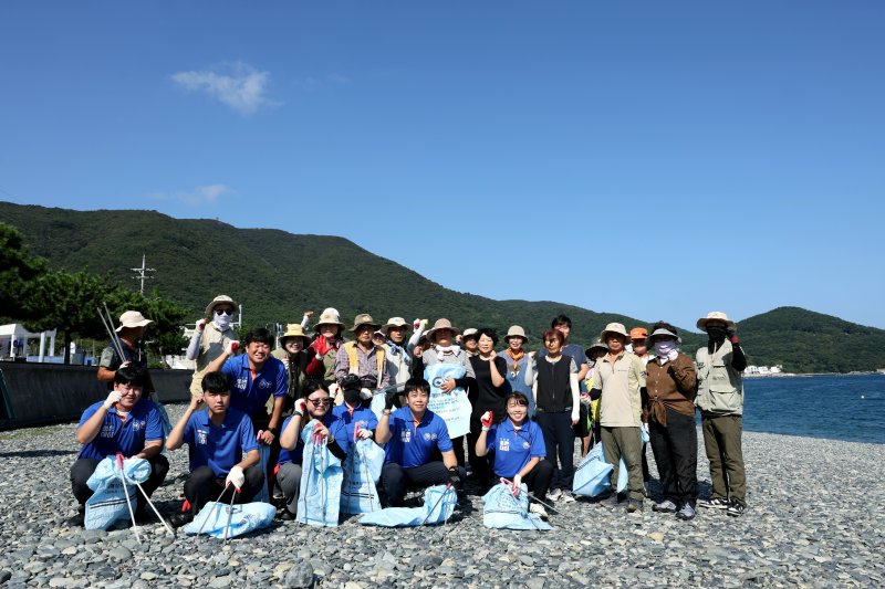 지난 9일 경남 거제시 학동흑진주해수욕장에서 진행된 환경정화 봉사활동 후 무학 좋은데이 봉사단원 등이 기념촬영을 하고 있다. 무학 제공