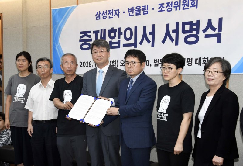 삼성전자와 반올림 관계자들이 2018년 7월 서울 서대문구 법무법인 지평에서 열린 '삼성전자-반올림-조정위 중재 합의서 서명식'에서 중재합의서를 들고 기념촬영을 하고 있다. fnDB