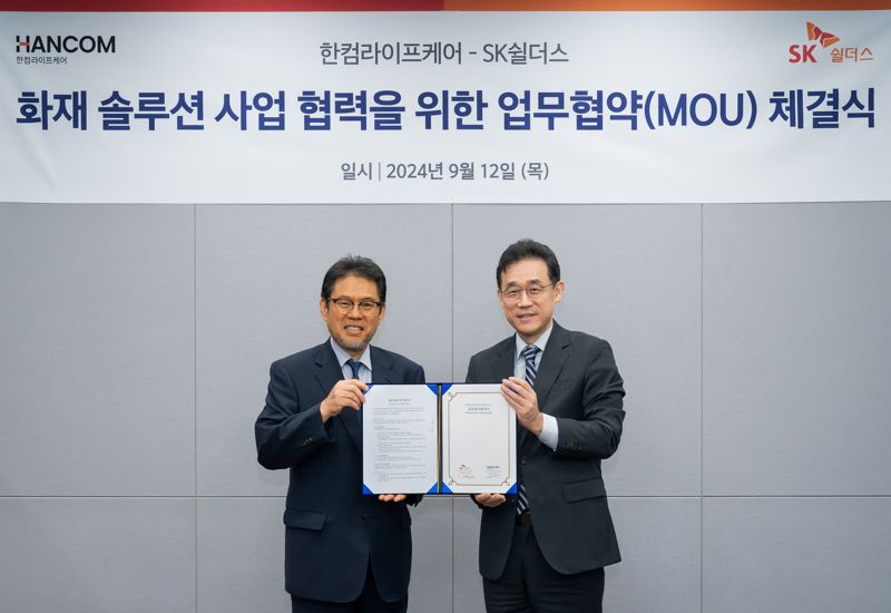 지난 12일 SK쉴더스 판교본사에서 SK쉴더스와 한컴라이프케어가 전기차 및 리튬 배터리 화재 예방 시스템 구축을 위한 협력을 진행했다. SK쉴더스 김진중 융합보안사업부장(오른쪽)과 한컴라이프케어 오병진 대표가 기념 촬영을 하고 있다. SK쉴더스 제공