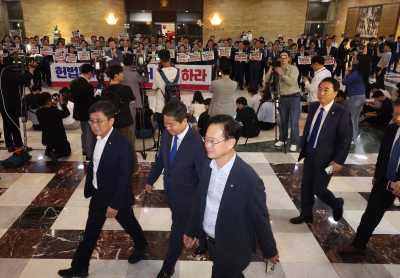 [서울=뉴시스] 고승민 기자 = 더불어민주당 의원들이 19일 서울 여의도 국회에서 열린 제418회 국회(정기회) 제8차 본회의에 참석하고 있다.이들 뒤로 국민의힘 의원들이 입법 폭주 및 포퓰리즘 규탄 등의 피켓을 들고 구호를 외치고 있다. 2024.09.12. kkssmm99@newsis.com