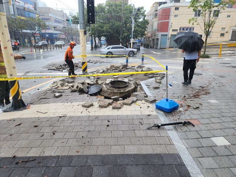 21일 오전 부산진구 연지동의 한 도로에서 맨홀이 열려 아스팔트가 파손돼 소방 당국이 안전조치를 취했다. 부산소방재난본부 제공