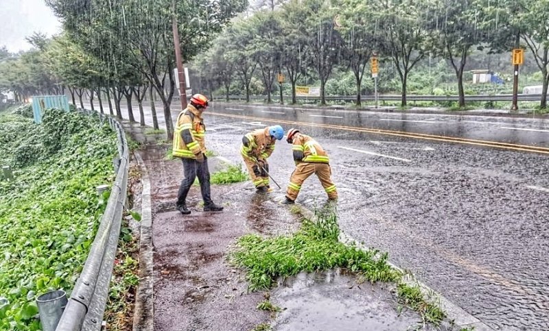 [울산=뉴시스] 구미현 기자 = 호우경보가 내려진 21일 울산 울주군 온산읍 덕산교차로에서 빗물 역류로 도로 맨홀 뚜껑이 열려 출동한 소방 대원이 안전 조치를 하고 있다. 2024.09.21. (울산소방본부 제공) photo@newsis.com *재판매 및 DB 금지