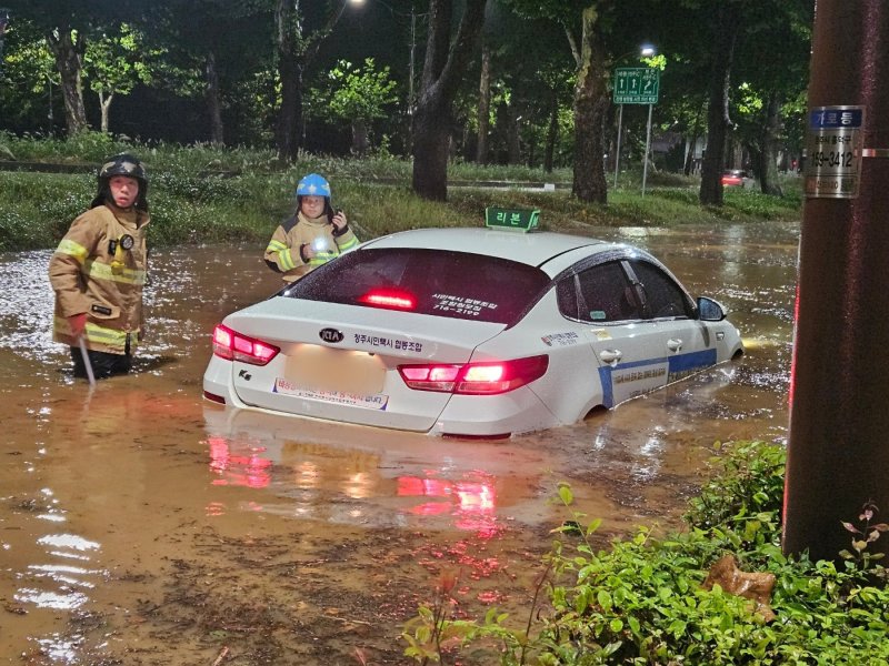 21일 오전 충북 청주시 석소동에서 집중호우로 인해 도로가 침수되어 출동한 소방대원들이 고립된 택시차량을 이동 조치하고 있다. (소방청 제공) 2024.9.21/뉴스1