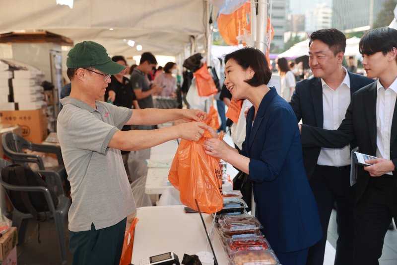 오영주 중소벤처기업부 장관이 지난 10일 서울 종로구 청계광장 일대에서 열린 ‘동행축제 전통시장 판매전’에서 판매부스를 둘러보며 제품을 구매하고 있다. 중기부 제공