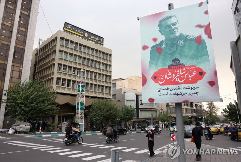 29일(현지시간) 이란 수도 테헤란 거리에 걸린 닐포루샨 IRGC 작전부사령관 추모 포스터 epa11632047 Iranians walk next to a poster of late Iranian Islamic Revolutionary Guard Corps (IRGC) commander, Brigadier General Abbas Nilforoushan, who was killed with late Hezbollah leader Hasan Nasrallah following an Israeli air strike, in Tehran