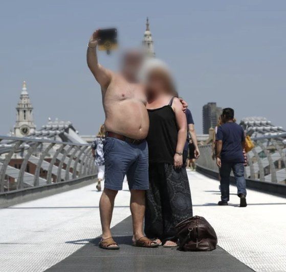 영국 런던의 밀레니엄브리지에서 웃통을 벗은 남성(왼쪽)이 일행과 기념 촬영을 하고 있다.<div id='ad_body3' class='mbad_bottom' ></div> 사진 더 선 홈페이지 캡처