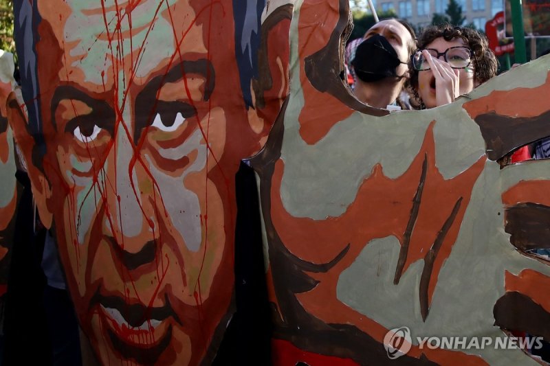 미국의 반이스라엘 시위 TOPSHOT - People hold an image of Prime Minister of Israel Benjamin Netanyahu with blood on his face as they demonstrate to mark one year of the war between Hamas and Israel in New York, on October 5, 2024. (Photo by Leonardo Munoz / AFP)