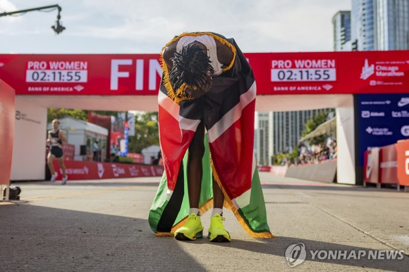 체픈게티, 2시간10분 벽 돌파 Ruth Chepngetich, from Kenya, lowers her head while wearing the Kenyan flag after crossing the finish line of the Chicago Marathon to win the women's professional division and break the women's marathon world record in Grant Park on Sunday, Oct. 13, 2024. (Tess Crowley/Chicago Trib