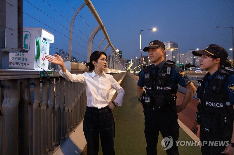 김건희 여사가 지난달 10일 '세계 자살 예방의 날'을 맞아 서울 마포대교에서 마포경찰서 용강지구대 근무자와 함께 '생명의 전화'를 살펴보며 대화하고 있다. /사진=대통령실 제공,연합뉴스